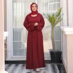 Woman is wearing cherry maroon abaya dress