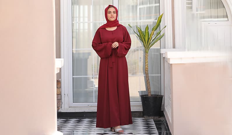 Woman is wearing cherry maroon abaya dress